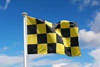 Drapeau avalanche damier en situation Drapeau avalanche à damier jaune et noir hissé sur mât en station de ski pour signaler risque marqué